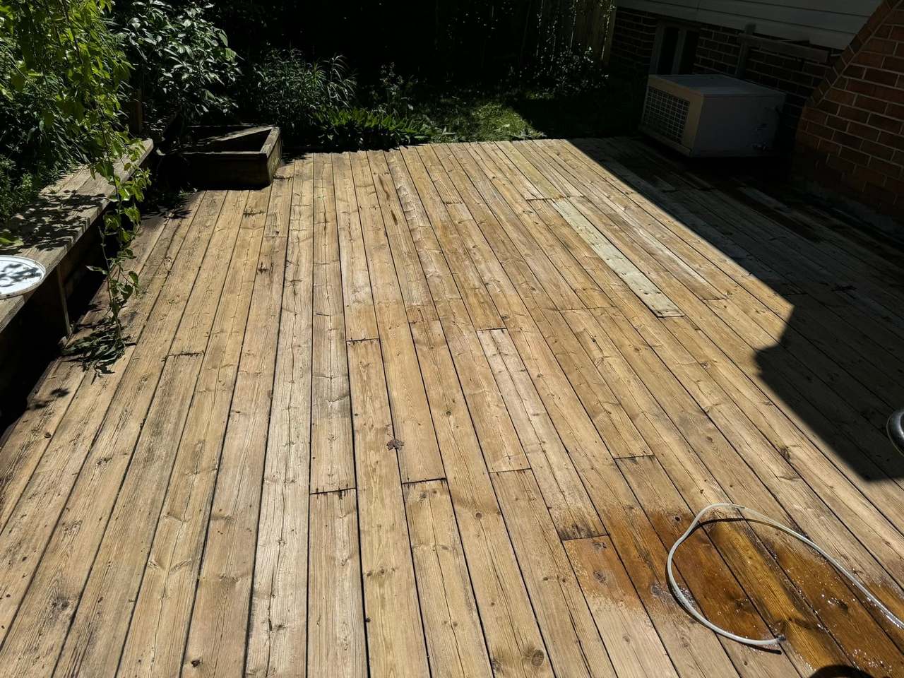 A weathered grey deck pressure washed back to clean, golden wood