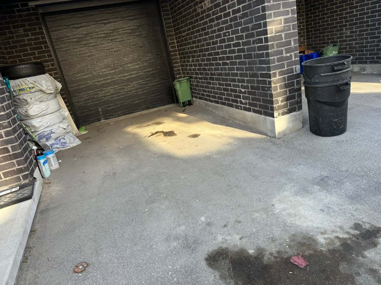 A driveway beside a garage cleared of bagged junk, a couch and bins, left clean