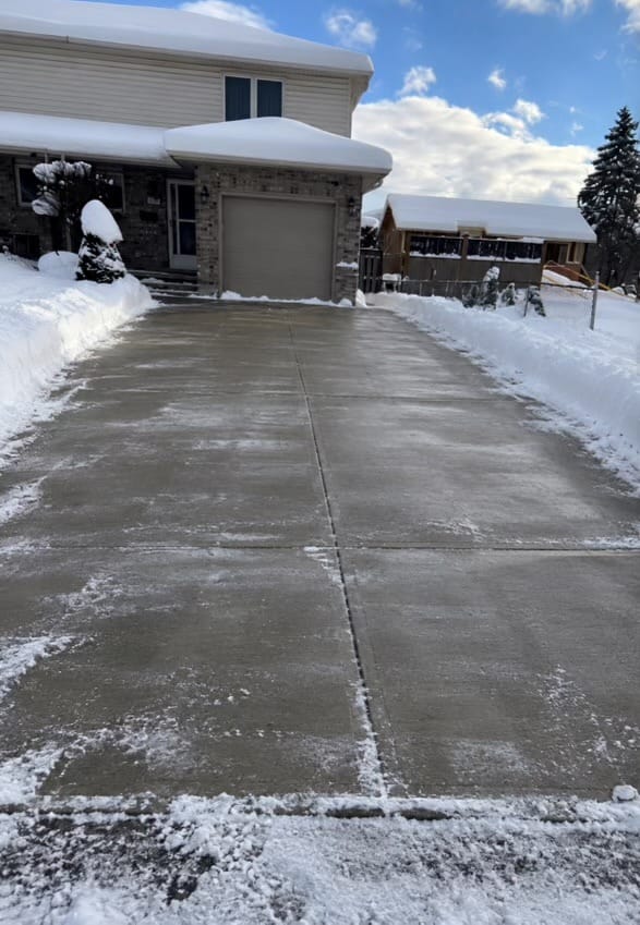 A driveway plowed back to bare concrete after a snowfall, London Ontario