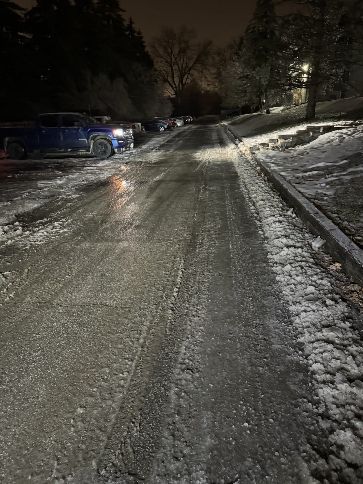 A shared lot and laneway plowed and salted overnight, clear black pavement between tall snowbanks