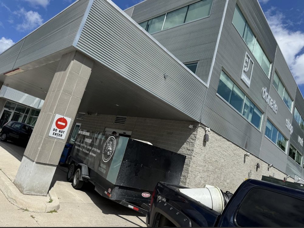 The branded LOW Price trailer parked at a multi-storey commercial building for a junk removal job
